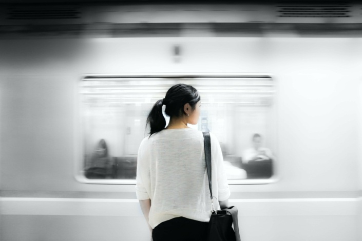 Eine Frau am Bahnsteig vor einem vorbeifahrenden Zug