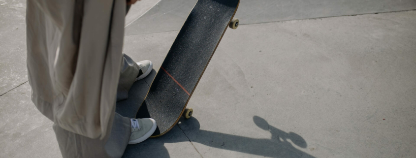 Eine stylisch gekleidete Person mit einem Skateboard steht oben auf einer Haflpipe mit einem Skateboard
