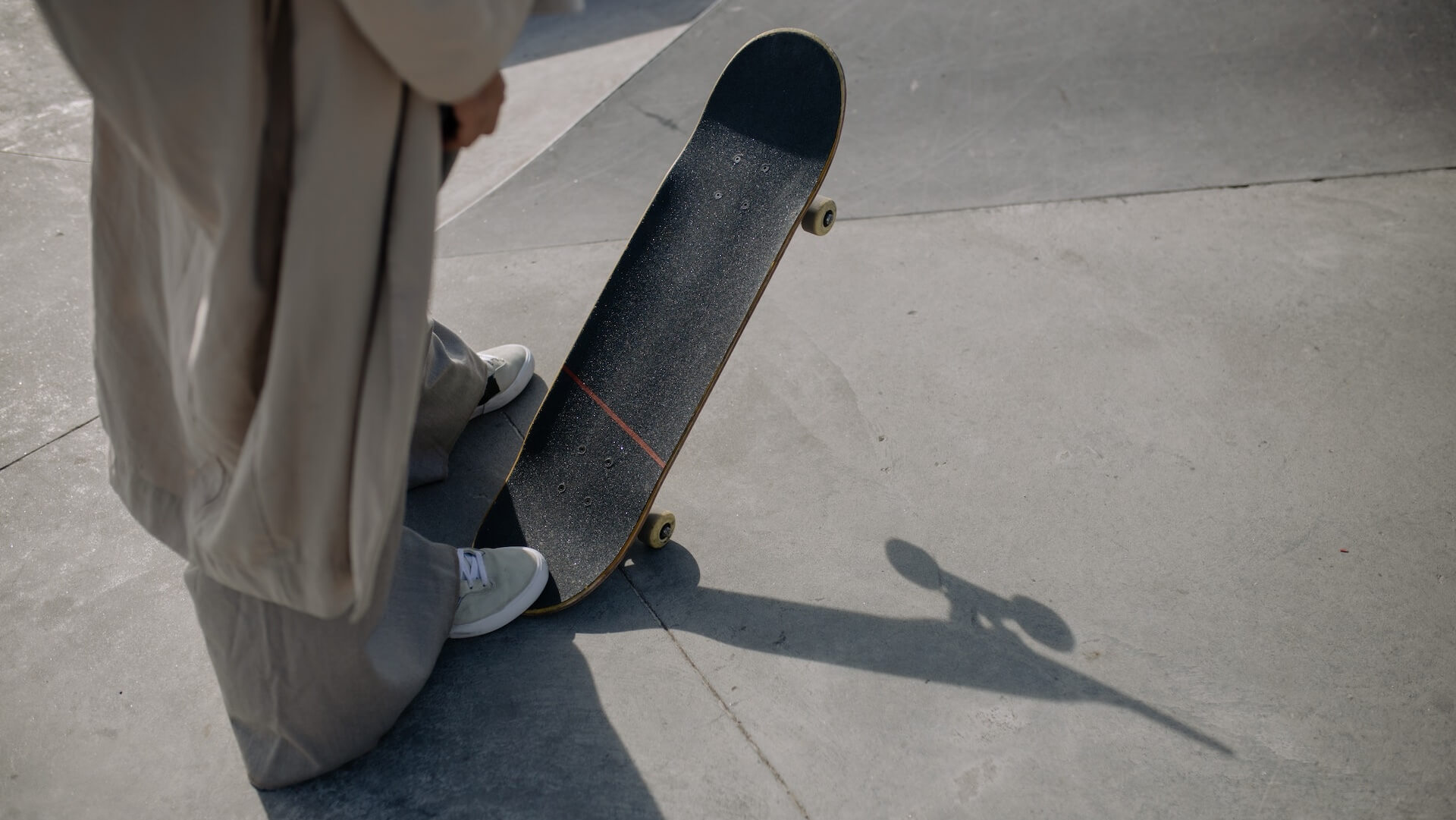 Eine stylisch gekleidete Person mit einem Skateboard steht oben auf einer Haflpipe mit einem Skateboard