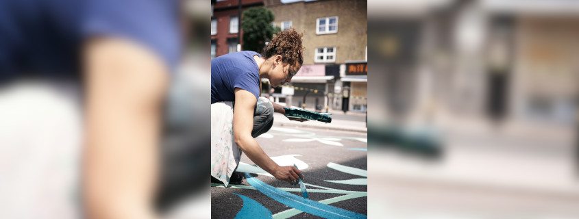 Frau in blauem t-shirt, malt auf dem Bürgersteig